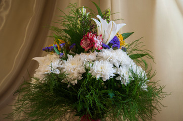 White lilyes, yellow and pink orchids, branch of lilac, chrysanthemums in the spring  tender bouquet on the background with green curtain