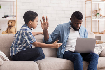 Little Afro Son Asking Attention From His Father Busy With Laptop