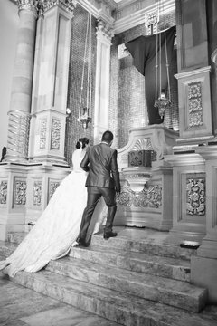 pareja reci&eacute;n casada subiendo al altar de una hermosa iglesia para agradecer a Dios su compromiso
