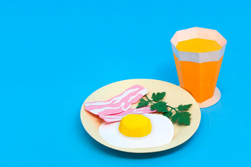 Paper fried eggs, bacon strips and orange juice
