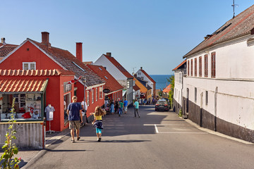Gudhjem,  Bornholm island, Denmark - June 29, 2019. Tourists on a street leading towards Baltic sea...