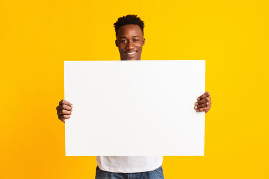Excited african american man holding blank poster