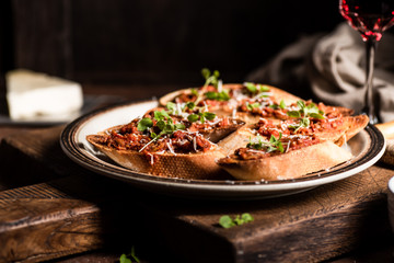 Italian bruschetta with olive paste, parmesan cheese and fresh oregano leaves. Rustick, wooden background.
