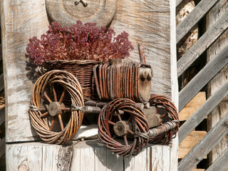 Decorative tractor made of wood twigs on a wooden pedestal in front of a woodshed