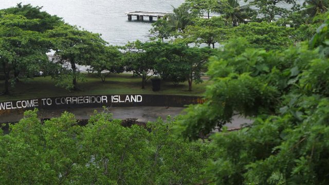 Pan left to reveal Corregidor Island welcome sign through jungle and trees