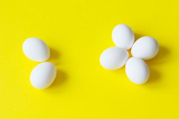 Six white eggs lie on a colorful yellow background.