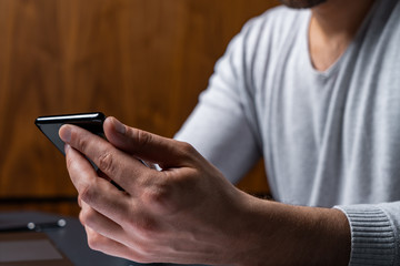 Man uses smartphone on work hours. Concept of cellular addiction.