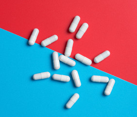 White medicine capsules on blue and red background