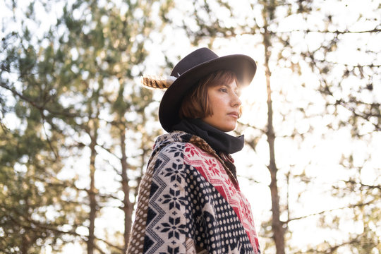 Yong hipster woman traveler in hat and poncho walking outdoors