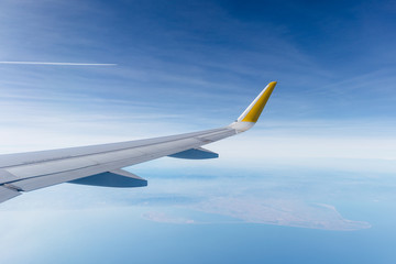 ala de avión de pasajeros airbus a320 sobrevolando el delta del ebro (cataluña, españa), con el cielo zul nublado de fondo.