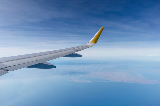 ala de avi&oacute;n de pasajeros airbus a320 sobrevolando el delta del ebro (catalu&ntilde;a, espa&ntilde;a), con el cielo zul nublado de fondo.