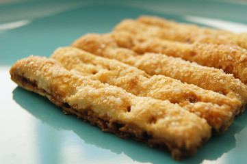 Delicious baked puff sticks with sugar and cinnamon on turquoise plate