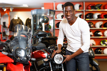 Fototapeta na wymiar Portrait of young man buying new motorcycle at modern showroom