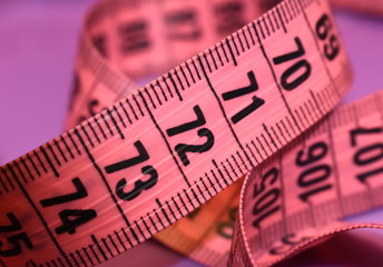 Part of a pink tailor's measuring tape on a blue background. Close up figures - 71, 72, 73.
