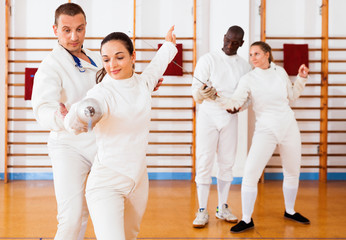 Woman fencer practicing new movements with trainer  at fencing room