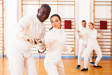 fencer practicing movements with african american trainer