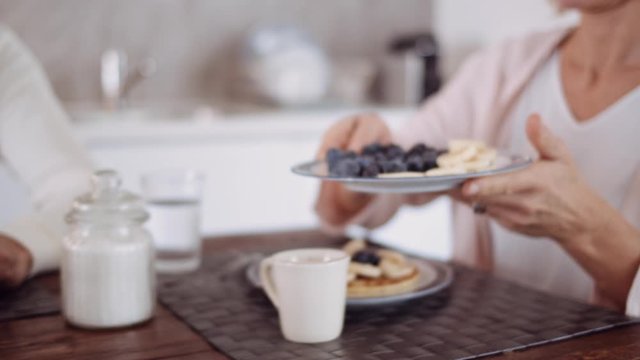 Slow motion shot of mature woman preparing pancake with fruits