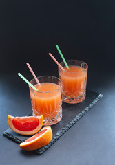 glass of red grapefruit juice cocktail  on a black  background