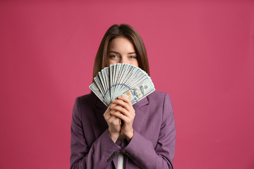 Young woman with cash money on pink background