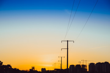 Sunset silhouette of electric towers in an area under construction, copy space.