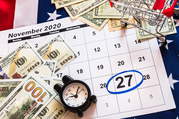 Black friday background with shopping cart and alarm clock with day on November 27, 2020 and American flag.