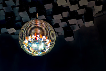 Dico ball on black cube style ceeling in nightclub with striped white and black walls lit by...