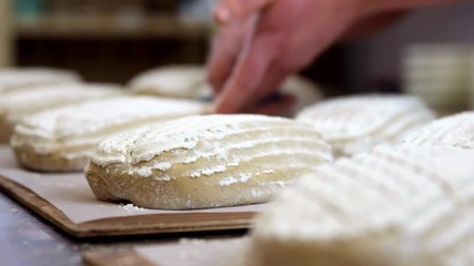 baker scoring proofed bread dough for the oven, close