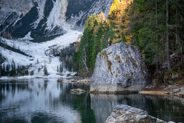 the young man with backpack near famous lake Braies in Italy with Dolomites mountains in background, Pragser wildsee