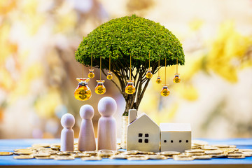 Home model and family put on the stack gold coin with growing as money bag of tree with interest value in the public park, Saving money or loan for business investment of real estate concept.
