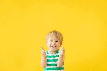 Portrait of happy child against yellow background. Summer vacation concept