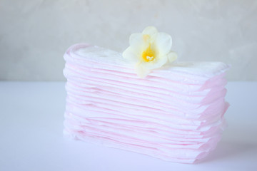 a stack of sanitary pads for every day on a light background, the concept of women's critical days, hygienic minimalism