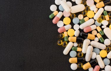 Pile of medicines pills closeup on black texture background. Concept of Health Care. Copy space.