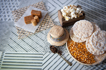Fototapeta na wymiar Popcorn, popcorn, straw hat, sweet paçoquinha, kid's foot, traditional ingredients in Brazilian June party. Clear background. Seen from the top. Horizontal. Space for your text.