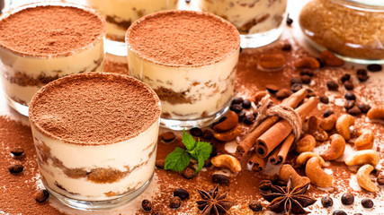 classical tiramisu dessert in a glass sprinkled with cocoa and decorated with coffee beans on a dark background, luxury dessert