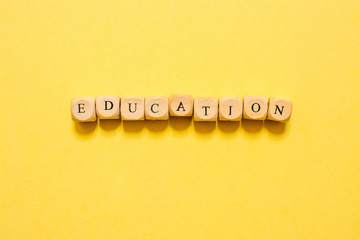 the word Education, text made with dice on yellow background