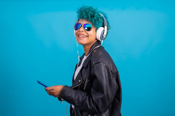 urban style young girl with mobile phone or smartphone and headphones isolated on color background