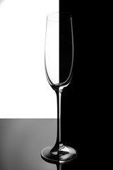 Empty champagne glass with reflection, on white and black gradient background. Club life concept. Magazine and commercial photo with place for text or design, festival and holiday food and drink