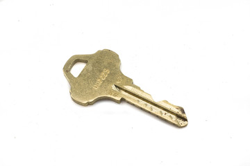 A brass house key, close up, isolated on a clean, white background.  Shot in macro.