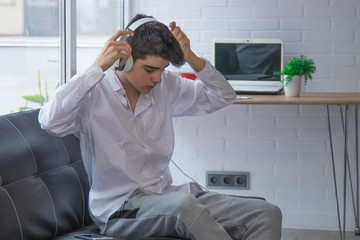 teenager or young student with mobile phone and headphones at home or apartment