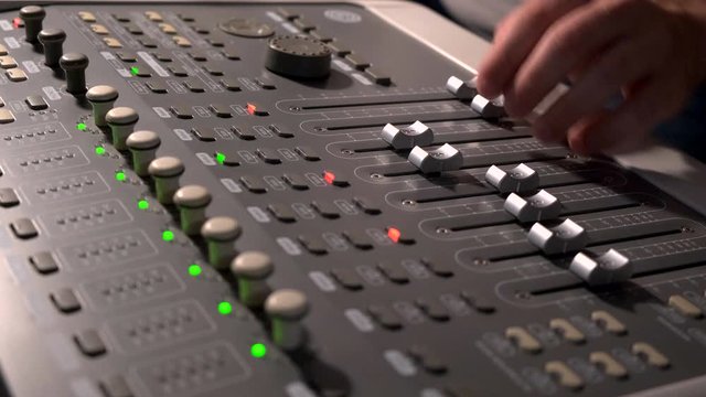 Close-up of a mixing console, the hand adjusts the faders. Sound director works in the studio. Professional recording studio. Recording Concept. 4K