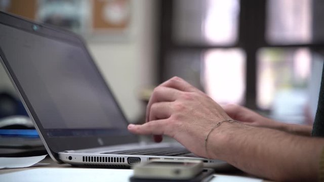 Hand typing on laptop keyboard in office in the morning, 4k computer static shot