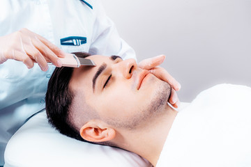 Ultrasonic face cleaning in a beauty salon for men. A man lies on the procedure for cleaning his...