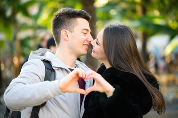 Young couple kissing while making a heart shape with their hands