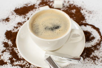 Espresso coffee on a white background with ground coffee and mini chocolates still Life . Selective focus.