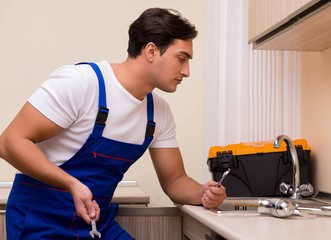 Young repairman working at the kitchen