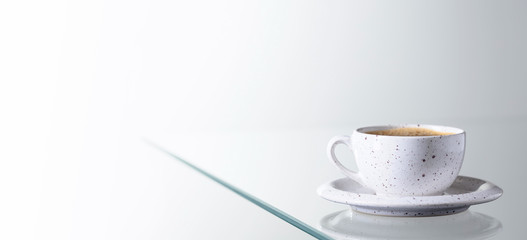 Espresso coffee in ceramic cup on a glass table.