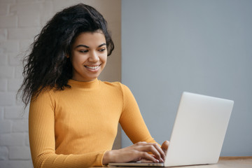 Beautiful African American woman using laptop computer, internet, watching training courses online....