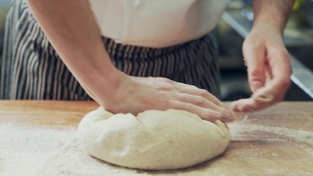 baker hands kneading dough on rye bread on wooden board
