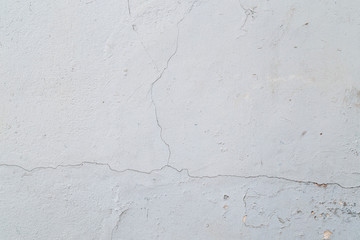 Close-up of a cracked concrete wall painted in white. High resolution full frame textured background.