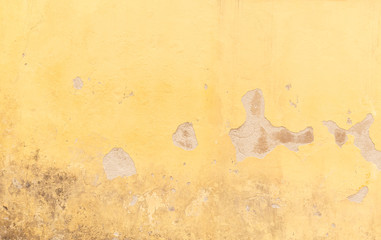 Close-up of a weathered and old concrete wall, plastering painted in yellow is broken. High resolution abstract full frame textured background.
